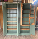 A large calke green double-door storage cabinet with open doors, showing multiple wooden shelves inside and a wooden ladder shelf mounted on the right door. 
