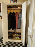 A 2 Door Hall Cupboard with doors open showing coat hooks and three shelves, containing clothing items and storage for shoes, set against a checkered floor and wall.