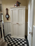 A white hallway storage cupboard with coat hooks and three shelves, displayed closed