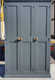 A traditional style solid pine wood storage cupboard withthree doors and a flat top, featuring wooden knobs and multiple internal shelves.
