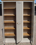 A traditional style solid pine wood storage cupboard with three doors and a flat top, featuring wooden knobs and multiple internal shelves.